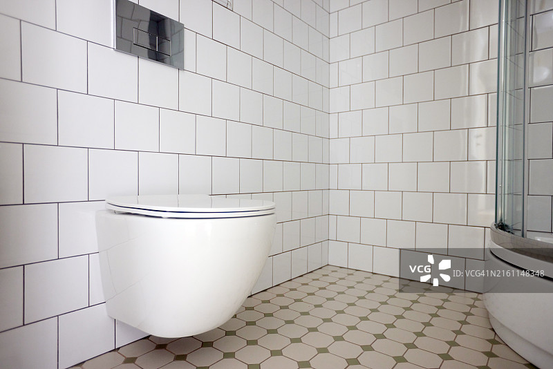 现代浴室，展示了时尚的壁挂式马桶和白色瓷砖，营造出豪华的极简主义美学图片素材