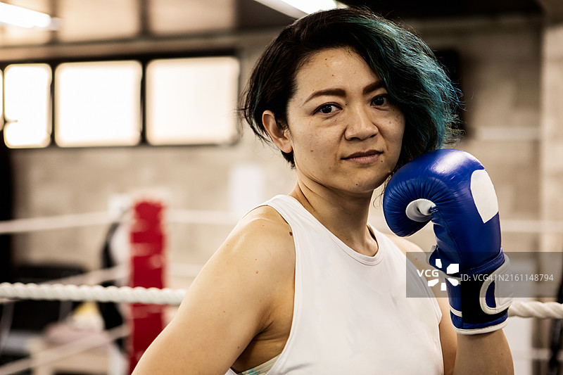 戴着拳击手套的日本女人在健身房的肖像图片素材
