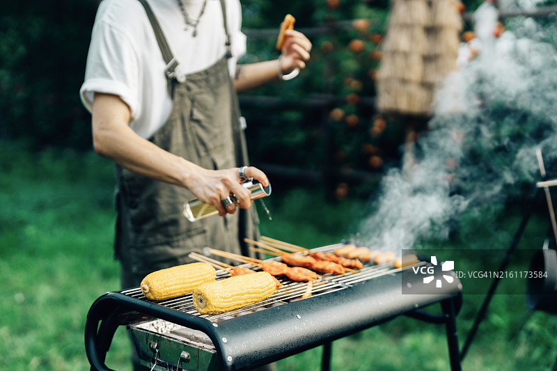 亚洲男人为朋友准备户外烧烤图片素材