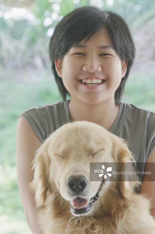 女孩拥抱金毛犬，微笑喜悦的肖像照图片素材