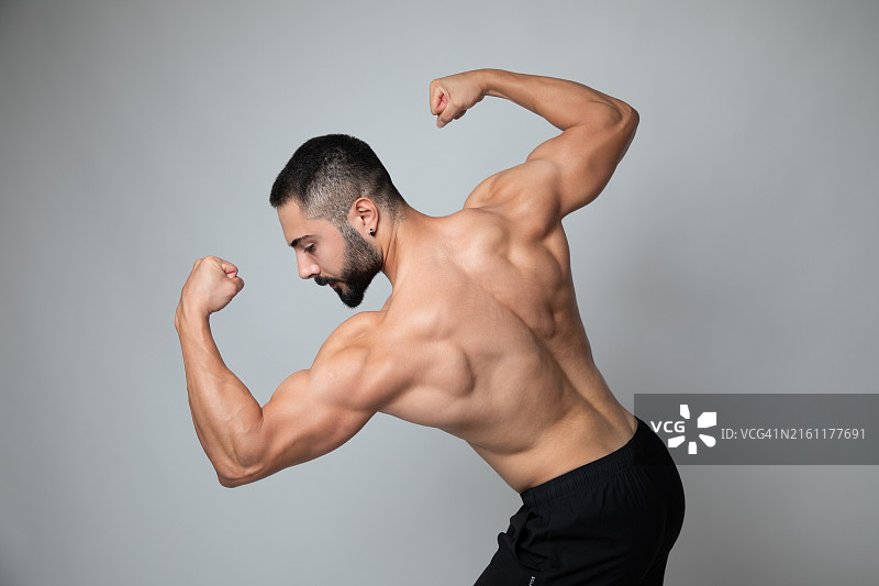 一名健壮的男人展示肱二头肌，秀出背部肌肉线条，强调力量和健康的背影图片素材