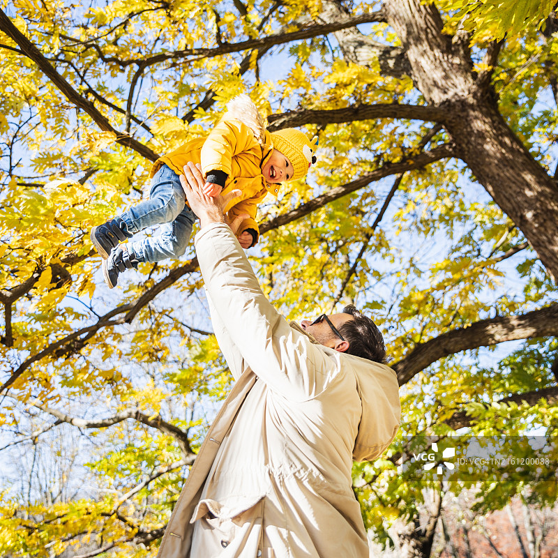 快乐的年轻父亲将他可爱的快乐男婴抛向空中图片素材