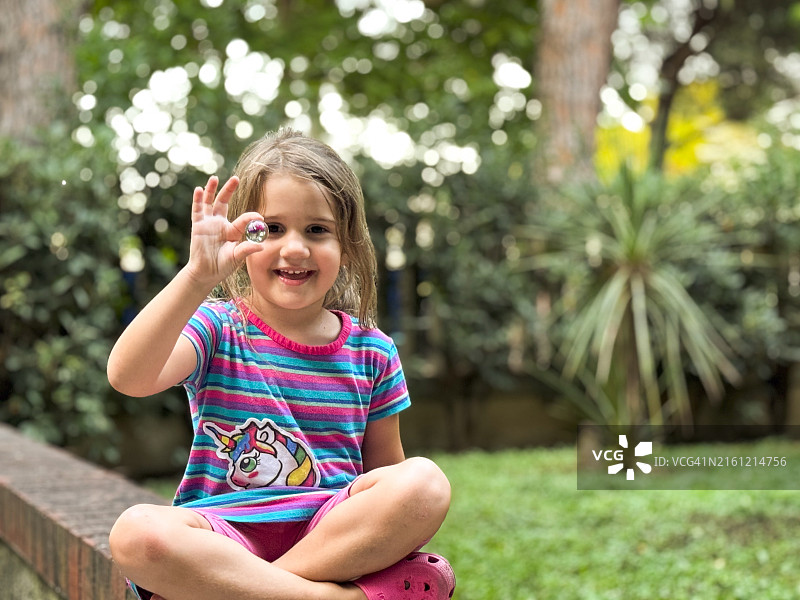 五岁女孩在户外玩弹珠的肖像图片素材