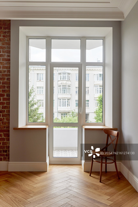 阳光明媚的公寓，配有大窗户和木椅图片素材