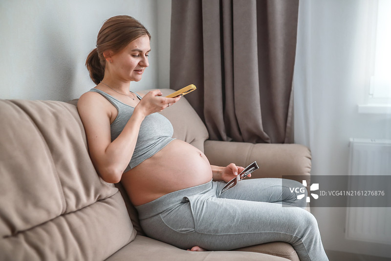 孕妇在家中沙发上查看胎儿超声照片图片素材