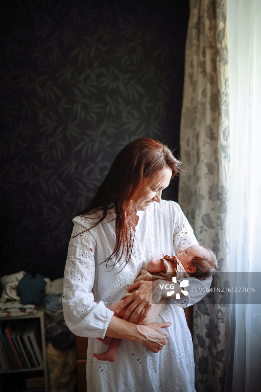快乐的中年母亲抱着新生女儿欢笑，真挚的母爱图片素材