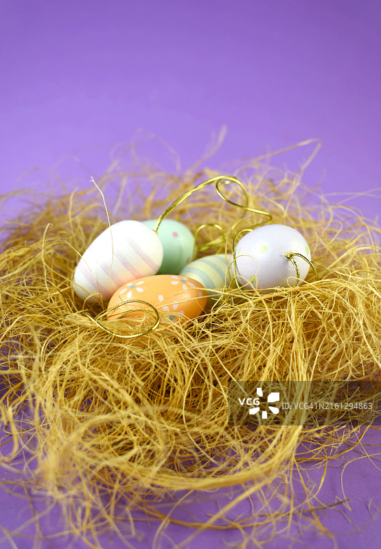 丁香背景上的稻草窝彩绘复活节彩蛋图片素材