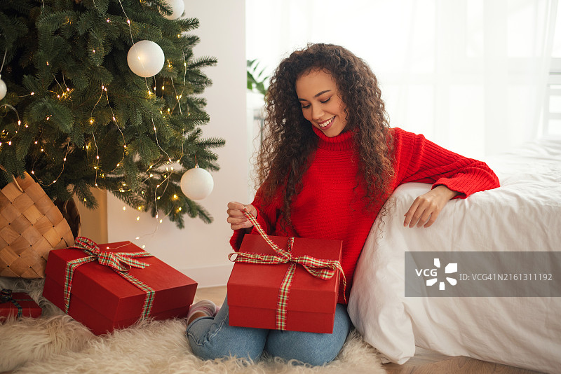 一位黑人女性正在拆礼物，新年，圣诞节，节日，圣诞节的早晨，惊喜图片素材