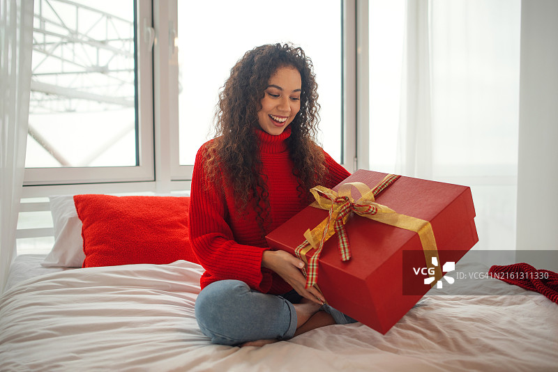 一位黑人女性正在拆礼物，新年，圣诞节，节日，圣诞节的早晨，惊喜图片素材