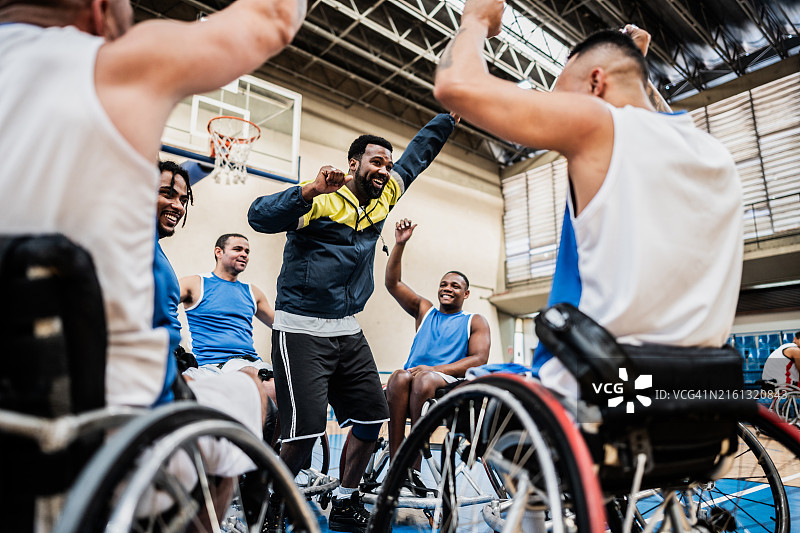 教练和轮椅篮球队员在运动场上庆祝图片素材