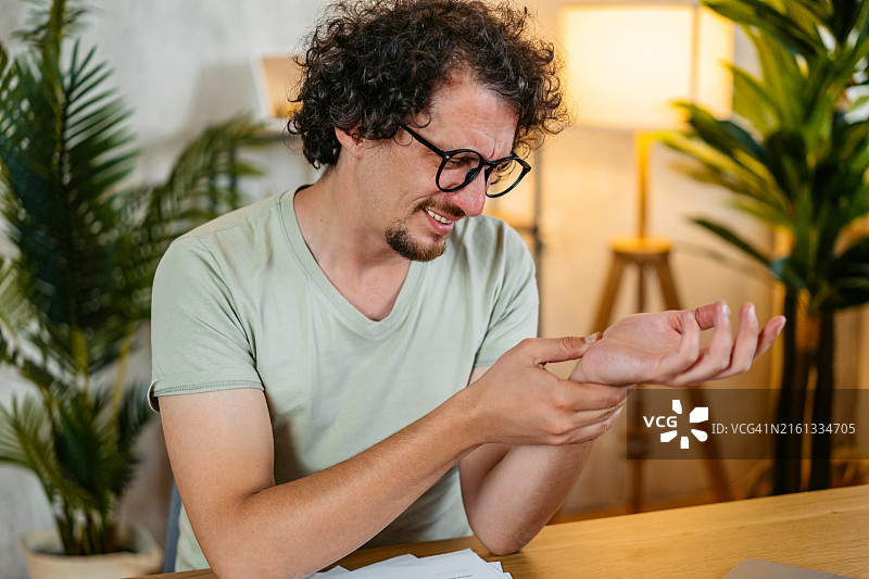 中年男人在家坐在厨房的桌子旁挠皮肤图片素材