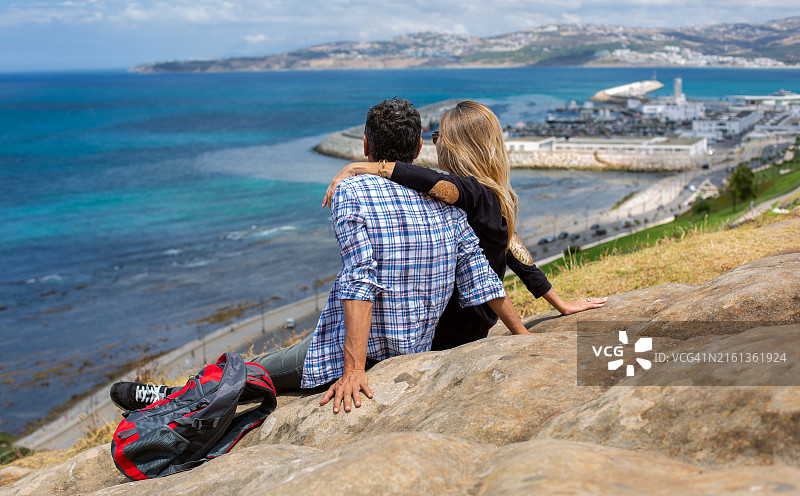 情侣在摩洛哥丹吉尔的腓尼基墓休息，眺望大海图片素材