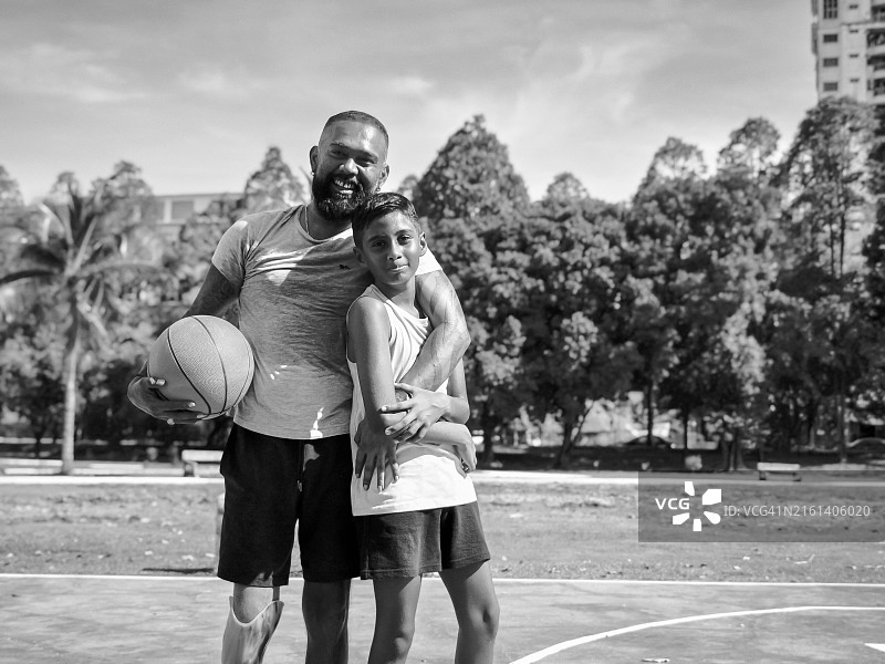 快乐的印度男孩和父亲站在篮球场上图片素材