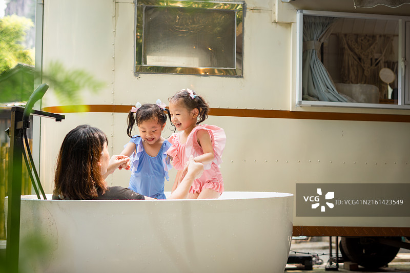 欢乐的双胞胎姐妹在户外浴缸玩耍图片素材