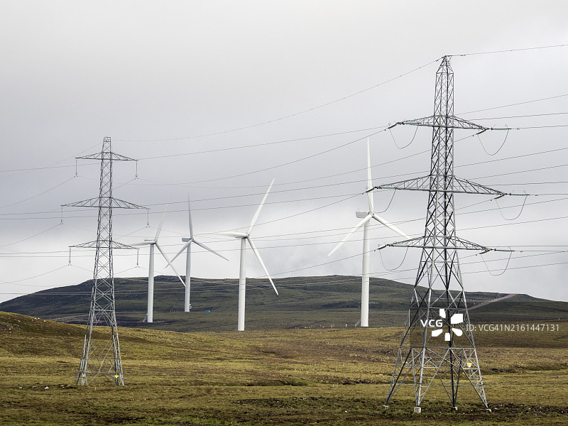 苏格兰斯特拉斯迪恩荒原上的风力涡轮机和输电塔图片素材