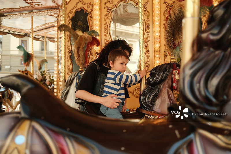 母亲抱着她的男婴骑旋转木马图片素材