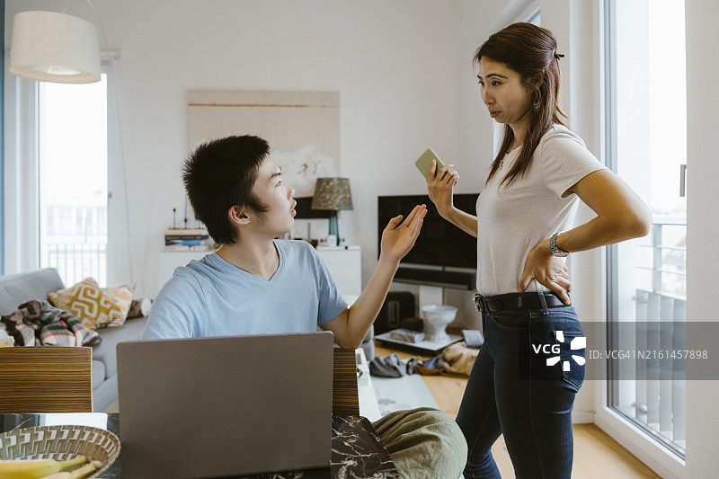 母亲在家学习时从儿子手中拿走智能手机图片素材