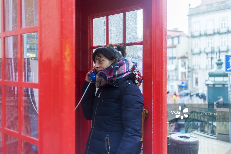 在电话亭里的年轻漂亮女孩，在雨天里打电话图片素材