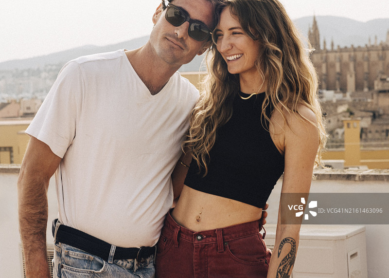 笑容满面的女人和戴着太阳镜的男友站在楼顶图片素材