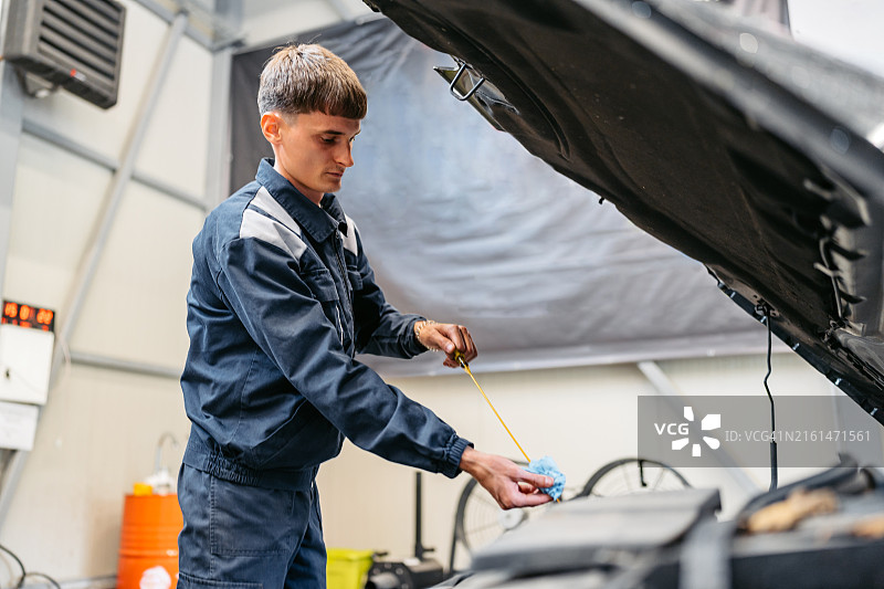 年轻汽车修理工检查汽车发动机油图片素材