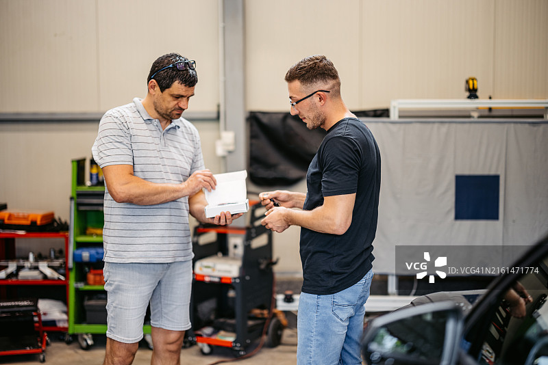 汽车修理工在车库里把汽车防盗锁发动机钥匙交给顾客图片素材