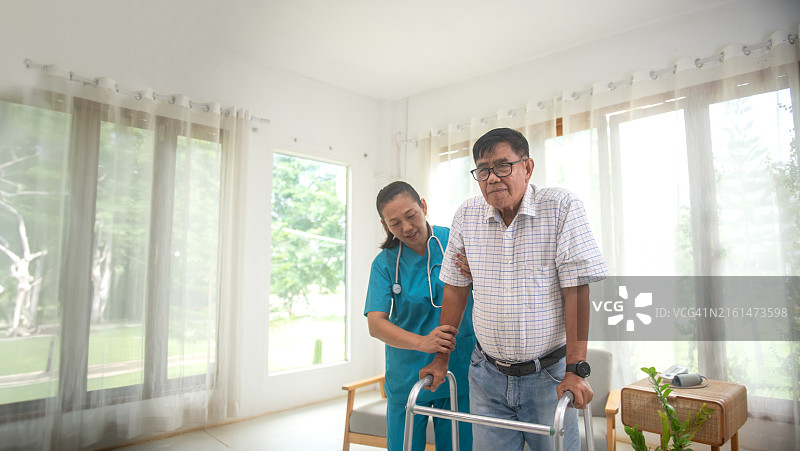 细心周到的护士帮助老年亚洲男人在家练习走路图片素材