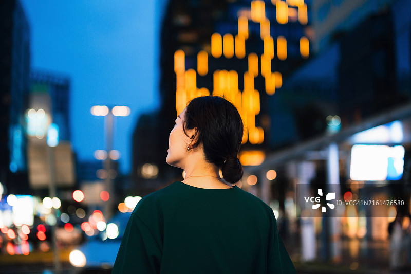 在繁华的市中心街道上眺望远方的年轻亚洲女子背影图片素材