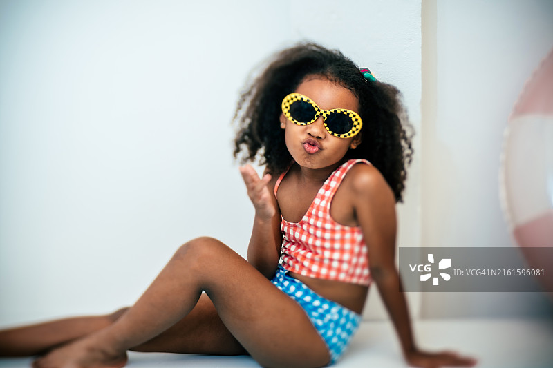 非洲女孩坐在泳池旁，把脚放在水里图片素材