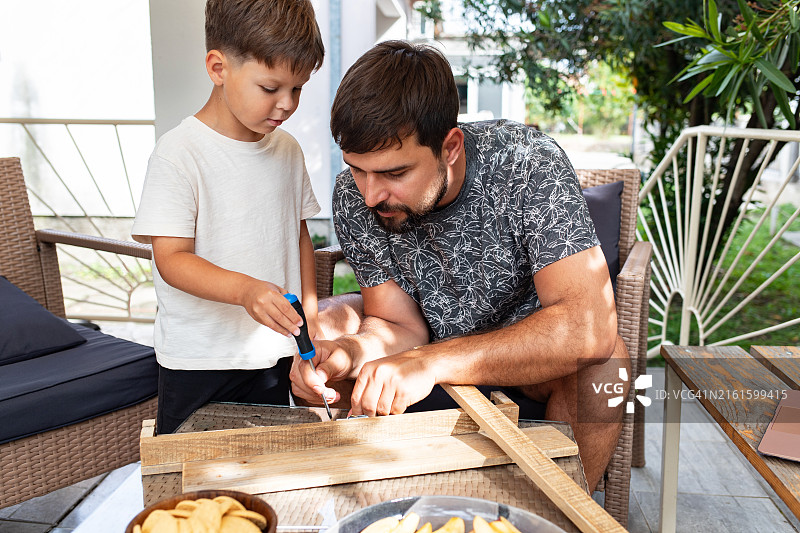年轻人教六岁男孩如何拧螺丝制作木质结构图片素材