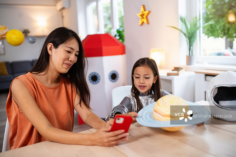 妈妈和女儿通过手机进行线上太空知识学习图片素材