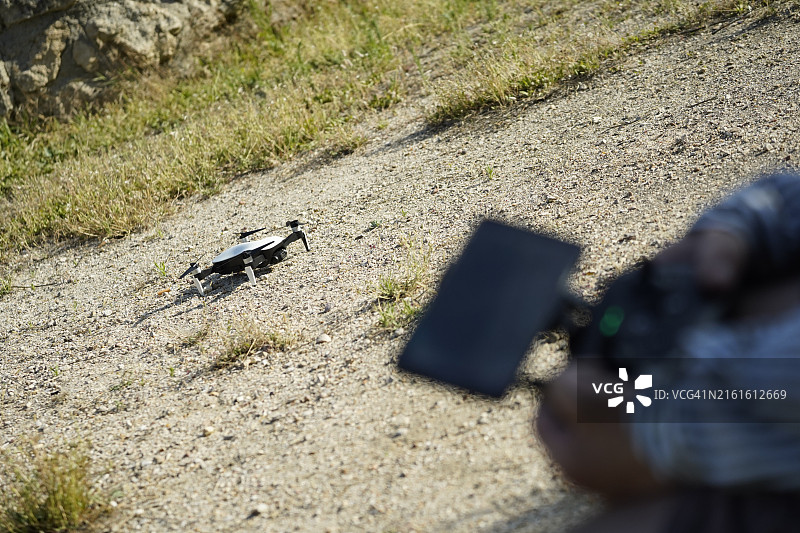 停留在地面上的无人机、手和控制器图片素材