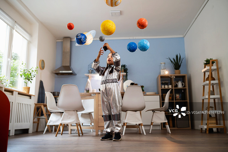 身穿宇航服的女孩在家玩耍，想象太空旅行图片素材