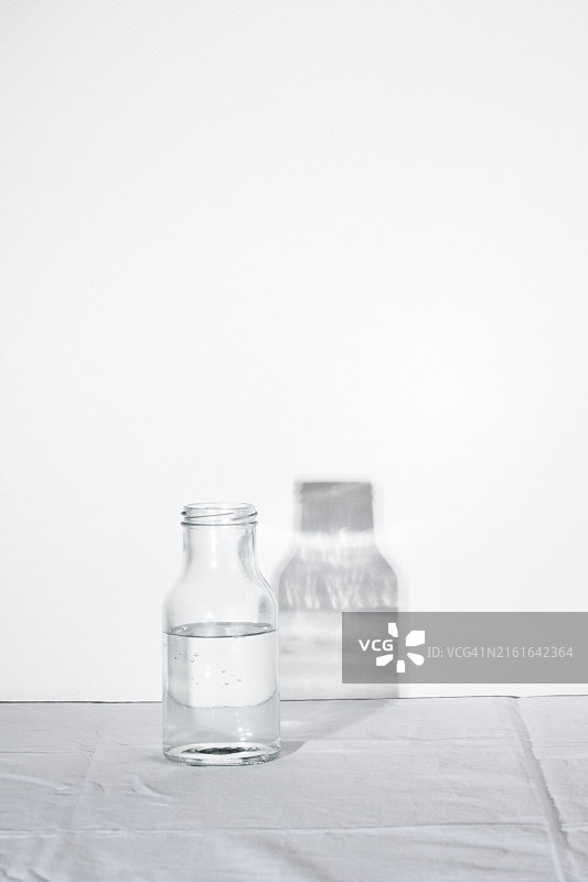 白色背景上的透明空玻璃水瓶和阴影（硬光），纯净水概念图片素材