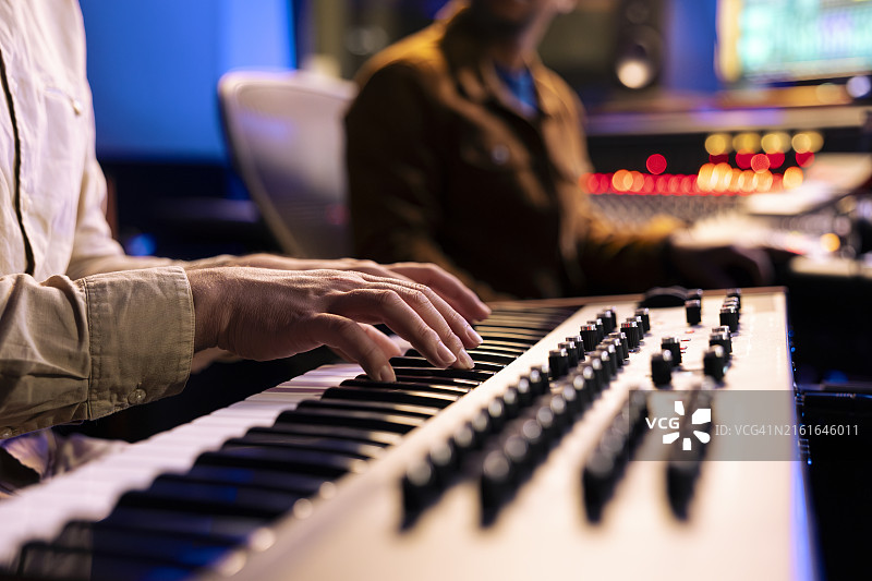男歌手在电子键盘钢琴上弹奏音符图片素材