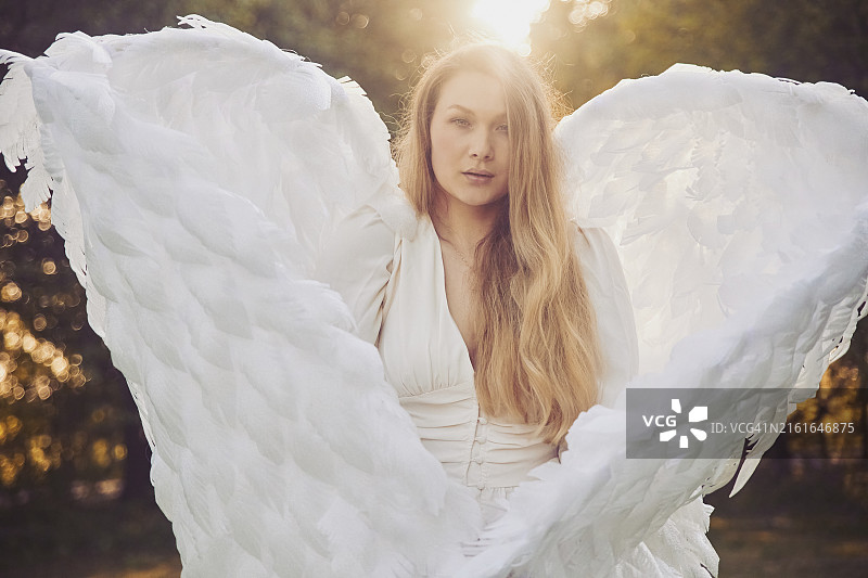在傍晚花园里打扮成天使的美丽女孩图片素材