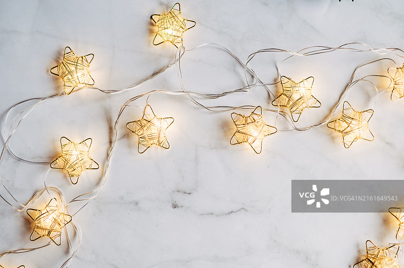 抽象背景中冷杉树枝上悬挂的圣诞星灯串图片素材