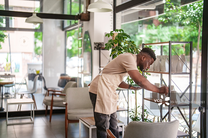 咖啡店员工使用平板电脑整理烘焙咖啡包装图片素材