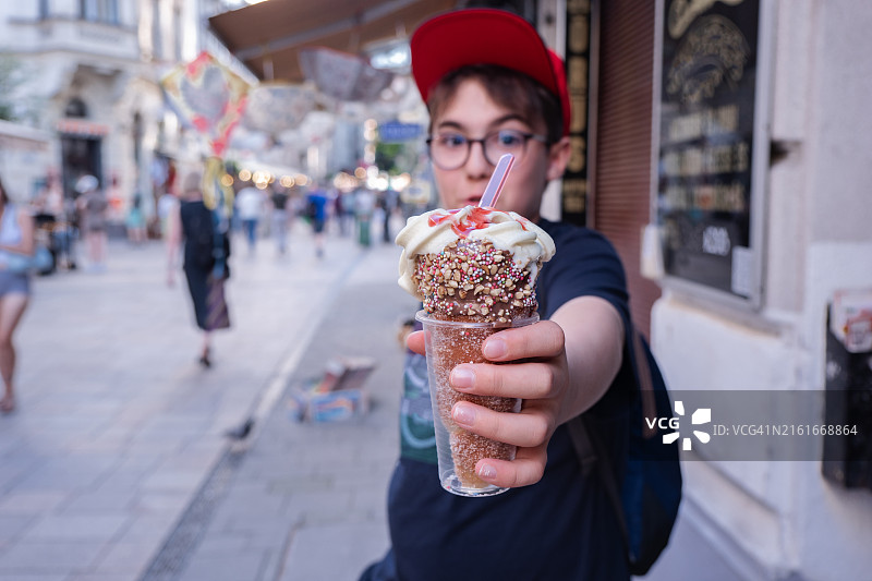 展示美味冰淇淋烤面包圈的游客男孩图片素材