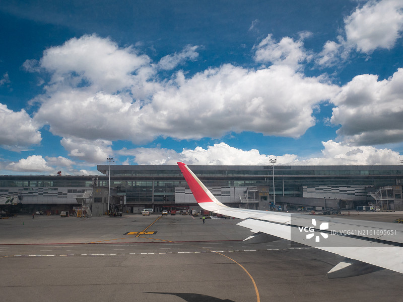 飞机起飞时掠过跑道，背景是肥沃的绿色土地和多云的天空图片素材