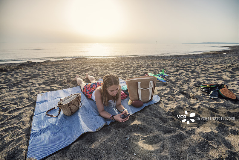 在海滩上使用智能手机的少女图片素材