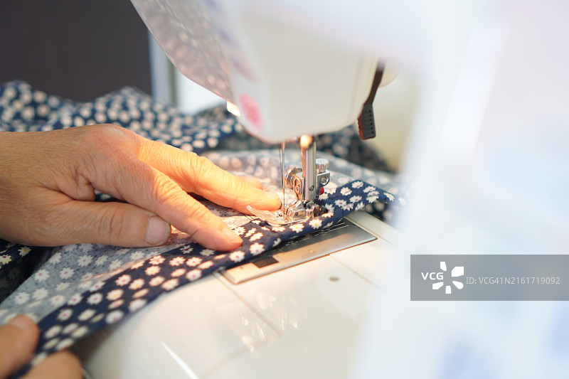 缝纫机特写：女士使用缝纫机缝制黑色布料图片素材