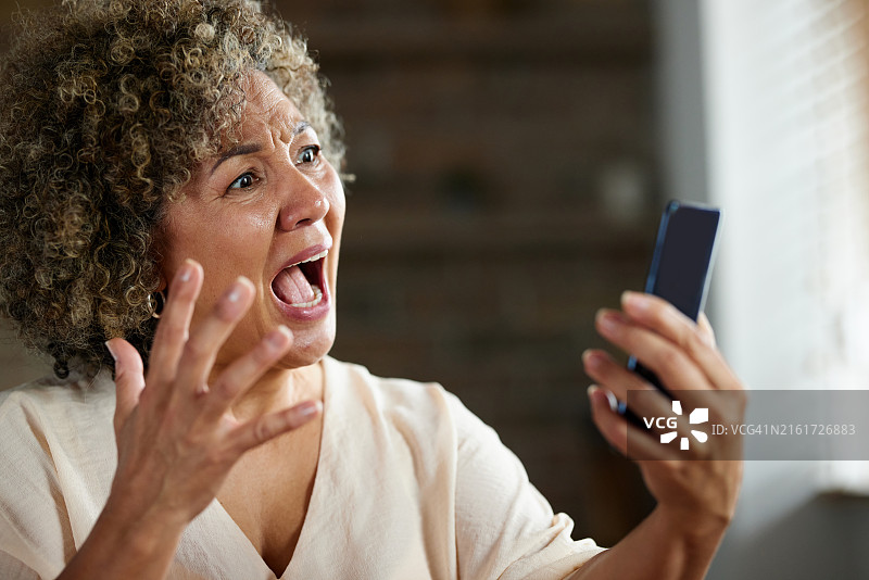 不高兴的成熟的女人在家里通过电话会议和别人争吵。图片素材