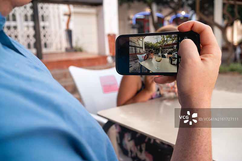 父亲在户外咖啡馆给孩子和葡萄酒拍照图片素材