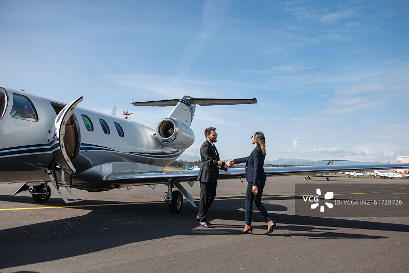 女商人走下私人飞机，飞行员迎接图片素材