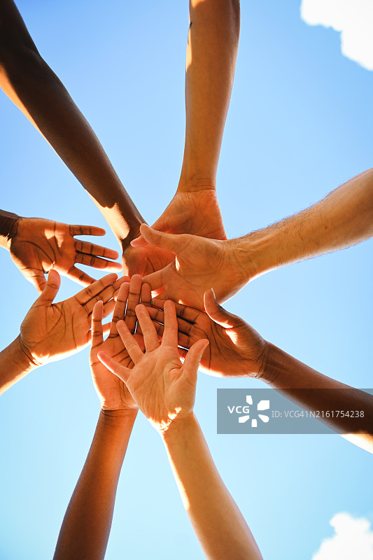 不同种族的人在蓝天下伸出双手图片素材