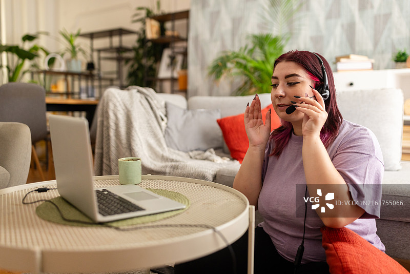 在家中办公室戴着耳机进行虚拟通话的女人图片素材