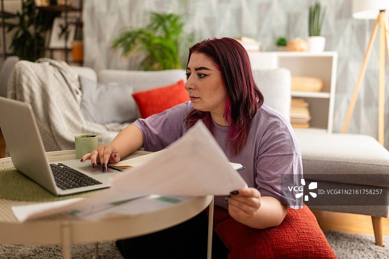 留着紫色头发的女人在家用笔记本电脑工作图片素材