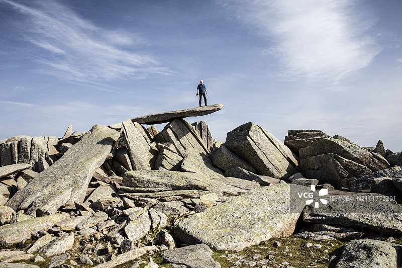 男子攀登悬臂石，位于英国威尔士斯诺多尼亚格利德劳山脉图片素材