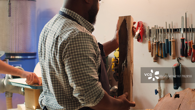 橱柜工人评估木材，从架子上选择合适的工具图片素材