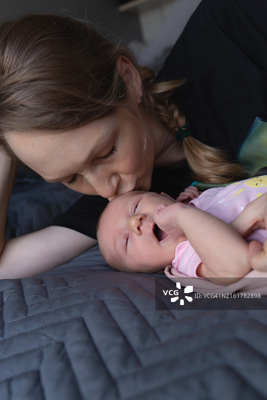 母亲亲吻新生儿的温馨时刻，捕捉纯粹的爱与温暖图片素材